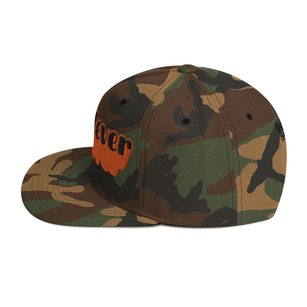 "Whatever" Snapback Hat in camo with bold orange embroidered text, perfect for streetwear fashion.